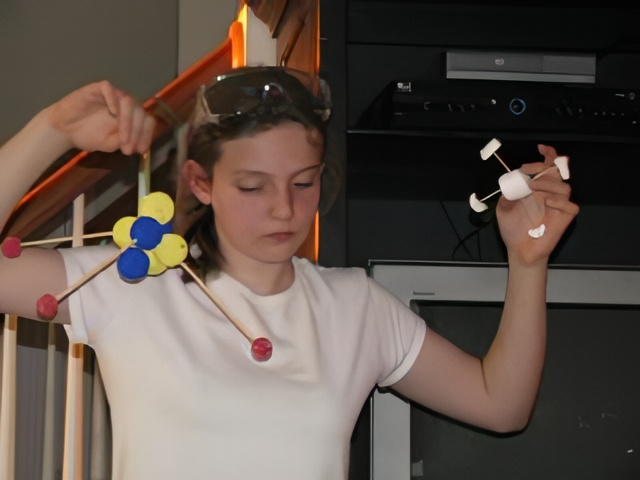 child showing molecule models made from styrofoam balls