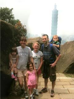 Family with four kids poses in front of a blue tower