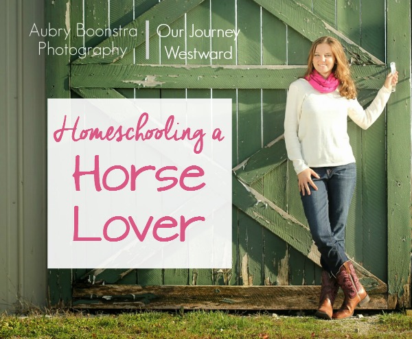 Girl in white sweater and pink scarf poses next to a green barn door. Photo used for a blog post about homeschooling a horse lover